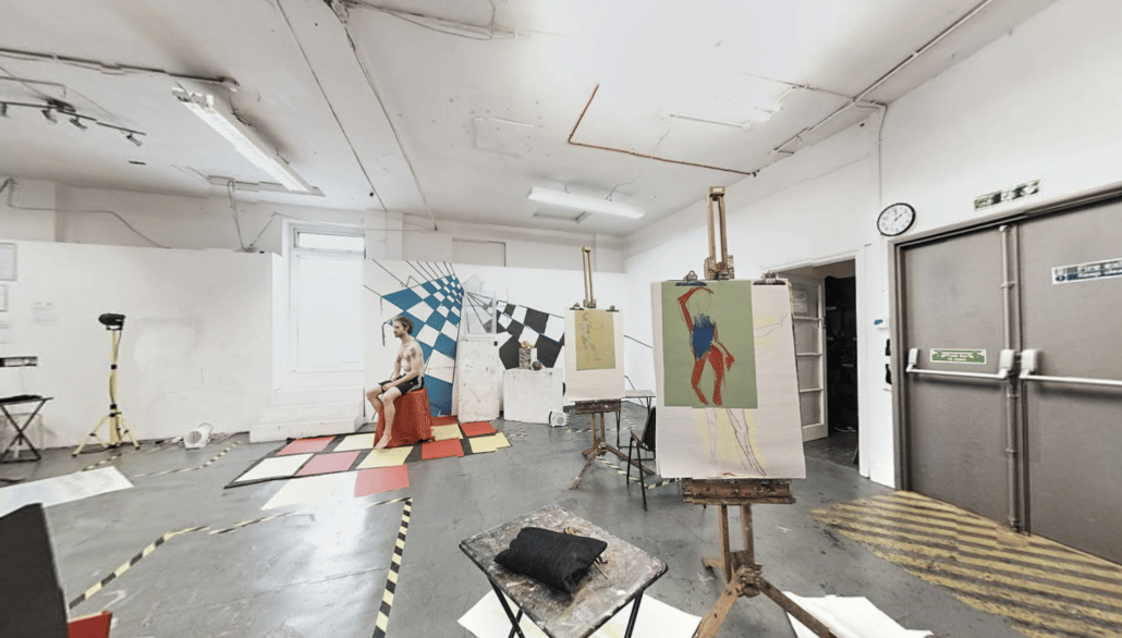 Wide angle photograph of a painting studio with life model and easels
